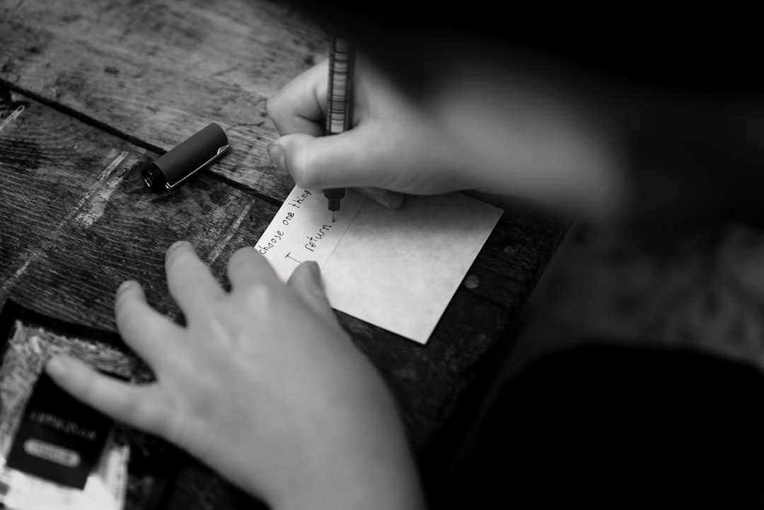 Person writing in a journal at a wooden desk